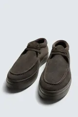 Zapato de cordones con parte superior de piel con acabado en serraje, detalle de bordón en el empeine, horma redonda y suela a contraste.