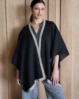 Ruana de tejido de punto en color crema con detalle de estrella grande en color verde lima en la espalda y bordes en tono arena.