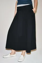 Falda midi color beige confeccionada en hilatura con mezcla de algodón. Presenta tiro medio, cintura con trabillas, bolsillos laterales ocultos en costura y cinturón del mismo tejido. Su diseño incluye un bajo acabado en línea evasé y cierre lateral con cremallera.