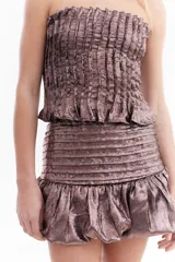 Top strapless de tela metálica con textura plisada, corte ajustado al cuerpo y diseño corto. Incluye una gargantilla a juego del mismo material.