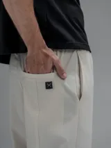 Pantalón cargo de corte oversize confeccionado en microfibra elastizada color beige. Presenta cintura elástica, bolsillos laterales y un bolsillo cargo con cierre de broche a presión. Incluye un sistema de elásticos con tancas en los tobillos para ajustar la apertura.
