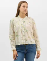 Blusa de algodón con estampado floral de flores silvestres sobre fondo claro. Presenta cuello redondo con detalle de puntilla, abotonadura frontal, canesú con frunces y mangas largas con puños elásticos decorados con puntilla.