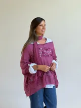 Sweater de punto magenta con diseño holgado, cuello redondo y detalles de encaje floral aplicado en el frente. Incluye una bufanda tipo choker integrada del mismo tejido.