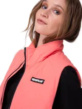 Chaleco acolchado Caterpillar color salmón, con cuello alto, cierre frontal con cremallera y bolsillos laterales con cierre. Presenta parche con el logo de la marca en el pecho.