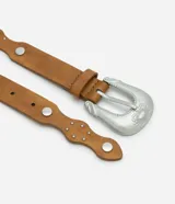 Cinturón estilo boho color tostado, con diseño de bordes ondulados y aplicaciones de tachas metálicas circulares. Cuenta con hebilla metálica de estilo western y múltiples perforaciones para ajuste.