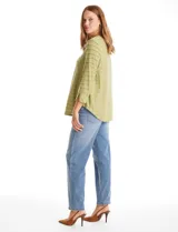 Blusa de silueta fluida en tejido shaggy con textura de franjas horizontales. Presenta cuello a la base, mangas tres cuartos con tajo lateral en el puño y ruedo redondeado con corte asimétrico, siendo más largo en la parte posterior.