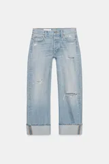 Jeans rectos de tiro medio en denim celeste con roturas y dobladillo vuelto en los bajos. Cierre frontal con botones metálicos y diseño de cinco bolsillos.
