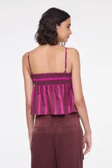 Top de algodón con diseño de rayas verticales en tonos bordó y fucsia. Presenta tirantes finos regulables, escote recto con fruncido elástico en el pecho, botones frontales decorativos y corte acampanado.
