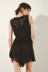 Top sin mangas de mesh con escote redondo y bordados florales hechos a mano a tono. Presenta un diseño sin forrería.