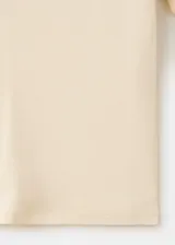 Camiseta de punto de algodón en color beige claro, con cuello redondo y mangas cortas. Diseño ajustado y estilo minimalista.