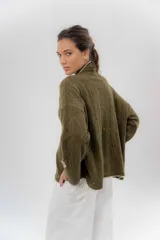 Saco tejido de lana color verde militar, con diseño de kimono de silueta relajada, mangas largas y delicados calados. Presenta detalles de cambio de color en los puños y el ruedo.