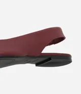 Zapatilla tipo slingback de cuero color marrón oscuro, con diseño de punta fina y talón descubierto con tira de ajuste.