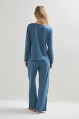Pijama de dos piezas compuesto por una remera de manga larga con cuello redondo y un pantalón de corte recto y holgado. Ambas prendas presentan un estampado de pequeños puntos oscuros sobre una base de color azul.