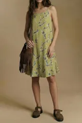 Vestido corto de tirantes finos, color verde pistacho con estampado de ramas y hojas en tonos gris/azul y blanco. Posee un corte suelto y ligero.
