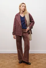 Chaquetón de lana color bordó con diseño de espiga y motas blancas. Tiene solapa, doble abotonadura frontal, mangas largas con detalle de correa y hebilla en los puños.