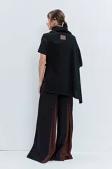 Poncho asimétrico de tejido de punto en color marrón, con cuello alto tipo polera y diseño sin mangas con aberturas laterales.