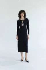 Vestido midi de manga larga en color negro, con un diseño ajustado al cuerpo y un detalle de abertura en el escote adornado con lentejuelas brillantes.