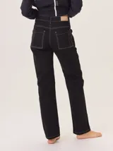 Jean recto de gabardina negra gastada, con pespuntes y atraques en hilo blanco contrastante.