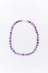 Collar corto de cuentas esféricas de color verde jade, engarzadas con hilo verde y detalles dorados.