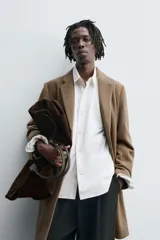 Abrigo de corte regular fit confeccionado en tejido compacto con mezcla de lana. Presenta cuello con solapas de muesca, cierre frontal de botonadura, bolsillos de vivo en la cadera y abertura central en la espalda.