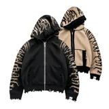 Hoodie con cierre frontal, confeccionado en tejido de punto 100% algodón. Es una prenda reversible con diseño de estampado gráfico en mangas y capucha, y presenta detalles de roturas intencionales en puños, ruedo y bolsillos.