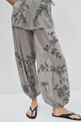 Pantalón de tiro medio confeccionado en tejido de tul transparente con forro interior corto. Presenta bordados florales con aplicaciones de lentejuelas, cintura elástica y bajo abullonado con acabado elástico.
