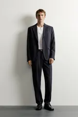 Blazer de corte relaxed fit confeccionado en tejido con lana, con solapas de muesca, manga larga con botones en los puños, bolsillos con solapa en la cadera, un bolsillo de vivo en el pecho y cierre frontal con dos botones.