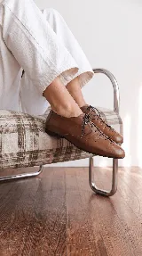 Zapato acordonado tipo oxford de cuero color off-white, con punta cuadrada, costuras decorativas y cordones finos al tono.