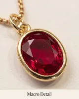 Collar de bronce con cadena fina y dije ovalado con piedra rubí sintética de corte facetado.