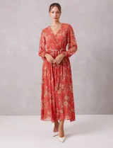 Vestido midi de gasa estampada con diseño floral, escote en V cruzado, cintura elastizada con lazo de ajuste y mangas largas con puños fruncidos. Incluye forro interno a tono.