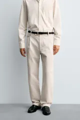 Pantalón de corte relajado confeccionado en tejido de algodón con estructura twill. Presenta pliegues frontales, bolsillos laterales y bolsillos traseros de doble vivo con botón. Cierre frontal con cremallera y botón.