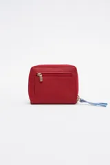 Billetera chica de cuero color rojo con cierre de cremallera y tirador celeste. Tiene bolsillo trasero y abertura al medio.