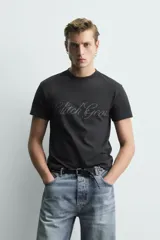 Remera negra de corte cropped, con cuello redondo y manga corta. Presenta estampado frontal con texto en efecto desgastado.