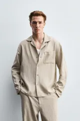 Camisa de corte relajado confeccionada en una mezcla de lyocell y lino. Presenta cuello bowling, manga larga con puño abotonado, bolsillo de plastrón en el pecho y cierre frontal con botones.