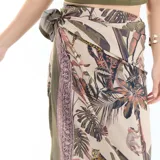Pareo largo de playa con diseño estampado de temática tropical y selvática en tonos beige, verde y marrón, con detalles de animales y vegetación.