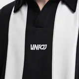 Buzo tipo polo de algodón, con diseño de bloques de color negro y blanco, cuello camisero y logo estampado en el pecho.