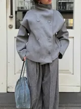 Chaqueta de paño color marrón oscuro, con diseño de doble botonadura frontal y cuello alto estructurado. Presenta mangas largas y un corte recto y holgado.