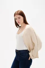 Cardigan de punto color natural, con cuello en V, cierre frontal con botones y diseño holgado. Presenta detalles de costuras decorativas bordadas a lo largo de las mangas y en los bordes.