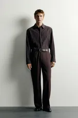 Camisa de manga larga con ajuste relajado, confeccionada en tejido de viscosa con textura de rayas verticales. Presenta cuello camisero, cierre frontal de botones y aberturas en el bajo lateral.