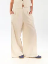 Pantalón de lino color beige, de corte ancho y relajado, con pretina elástica y cierre de botón.