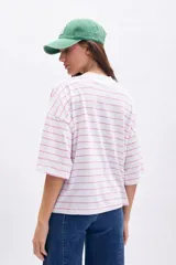 Remera blanca de manga corta ancha con cuello alto, estampada con finas rayas horizontales rosas.