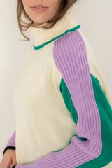 Buzo de punto con cuello alto, diseño de bloques de color en crema, verde y lila, con mangas largas y corte holgado.