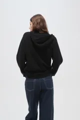 Sweater negro de punto con capucha, cierre frontal parcial y mangas largas. Presenta un diseño de tejido acanalado en la zona del cuello y los hombros.