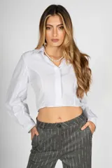 Camisa crop blanca de manga larga con cuello clásico y cierre frontal con botones.