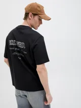 Remera básica de manga corta y color negro, con cuello redondo y diseño clásico para uso diario. Presenta un pequeño estampado tipográfico en el pecho.