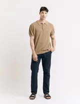 Remera color café de tejido de punto, con cuello polo y mangas cortas.