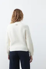 Polera de punto color marrón, con cuello alto y diseño de trenzas verticales en el frente y tejido acanalado en las mangas. Presenta mangas raglán y terminaciones acanaladas en puños y ruedo.