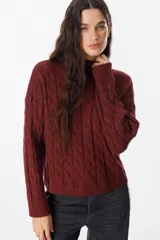 Sweater de tejido de punto con diseño de trenzas, cuello alto y mangas largas con puños acanalados.