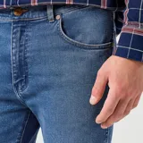 Pantalón de jean Wrangler corte slim, color azul medio, con bolsillos delanteros y traseros.