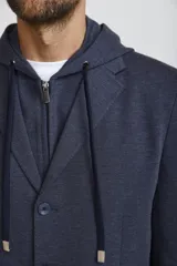 Blazer sport color gris claro con capucha integrada y cordones ajustables. Presenta solapas clásicas, cierre frontal con botones y bolsillos laterales de parche.